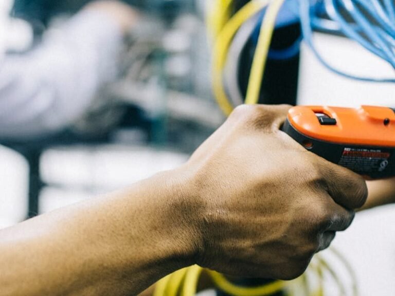 An engineer inspects network cables and connections in a server room, focusing with precision.